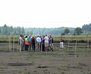 Fig 1. En grupp besökare samtalar med guiden Lotta Fernstål i ett av de markerade långhusen.