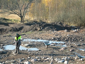 Mikael dokumeterar lagren som omger grophuset. Foto: Kenneth Svensson, Arkeologikonsult.