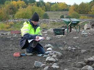 Charlotte dokumenterar en av de medeltida huslämningarna på Västergården. Foto: Kenneth Svensson, Arkeologikonsult.